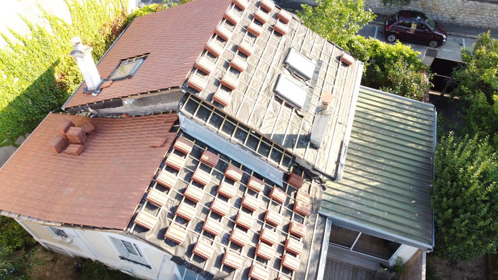 1. Couvreur du Compagnon de la Toiture posant une tuile plate de terre cuite sur une maison de Vulaines-sur-Seine